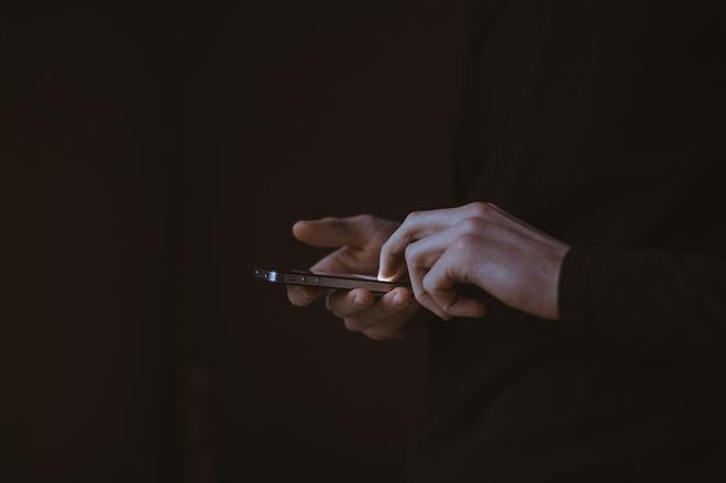 Twee handen met een mobile telefoon in het donker