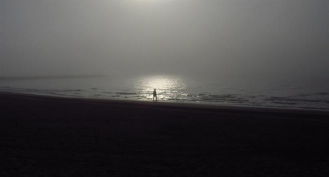 Persoon op het strand bij zonnsondergang