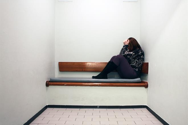 Afbeelding van vrouw op bankje in cel.