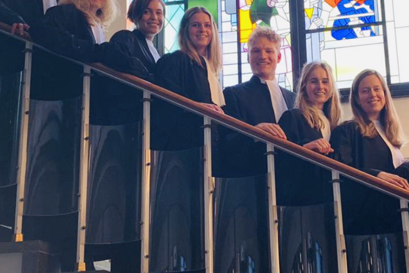 Medewerkers in toga op een trap.