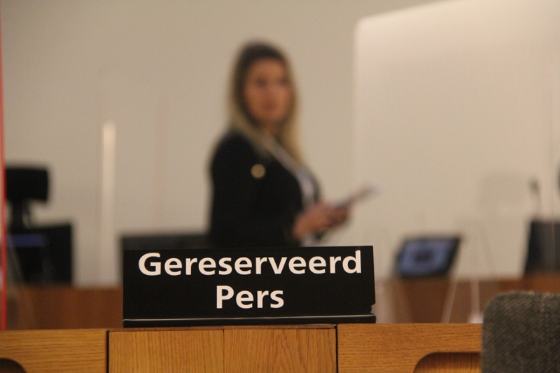 In de rechtszaal staat een bordje 'Gereserveerd – Pers'.