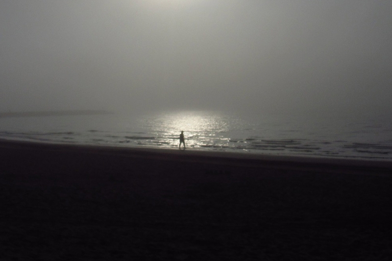 Persoon op het strand bij zonnsondergang
