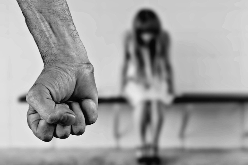 Zwart-wit foto van vuist met op achtergrond een vrouw op bankje