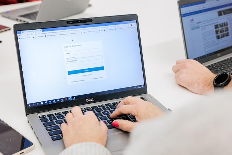 Handen die met laptop werken.